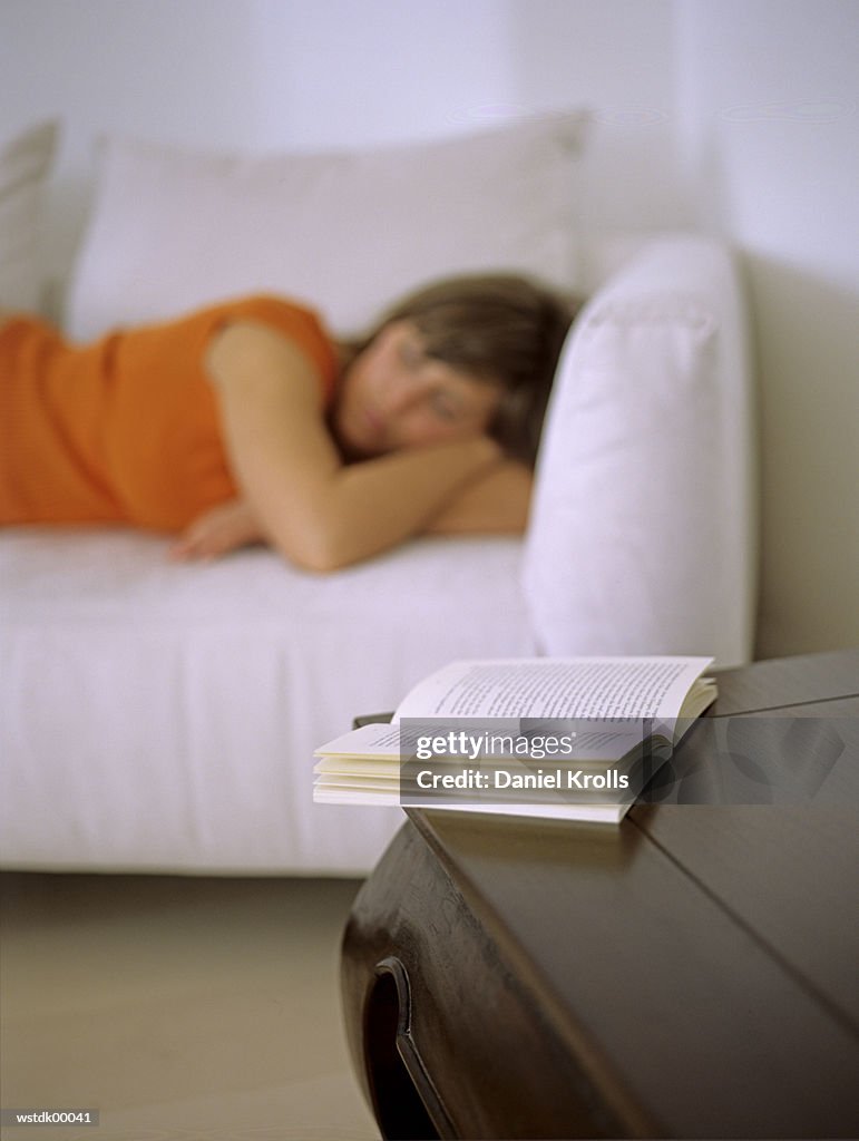 Woman lying on sofa, focus on open book