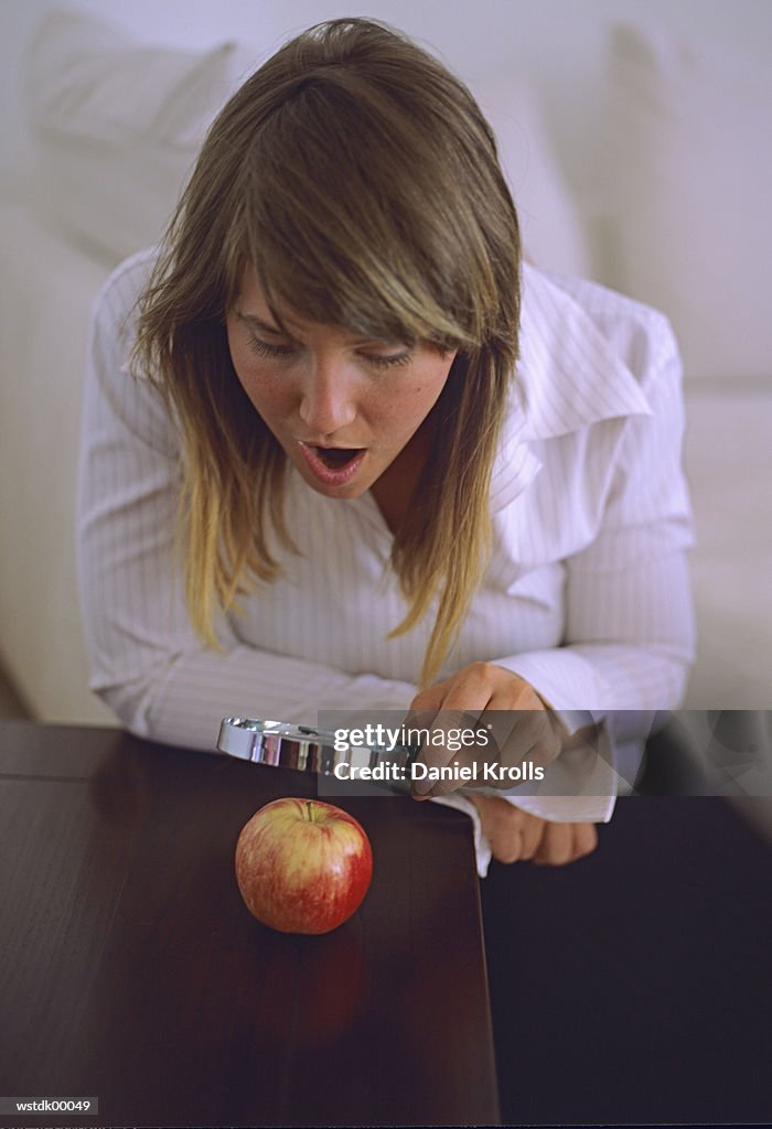 Woman looking at apple through magnifying glass