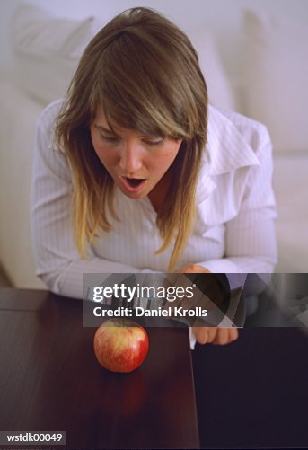 Woman looking at apple through magnifying glass Woman looking at apple through magnifying glass