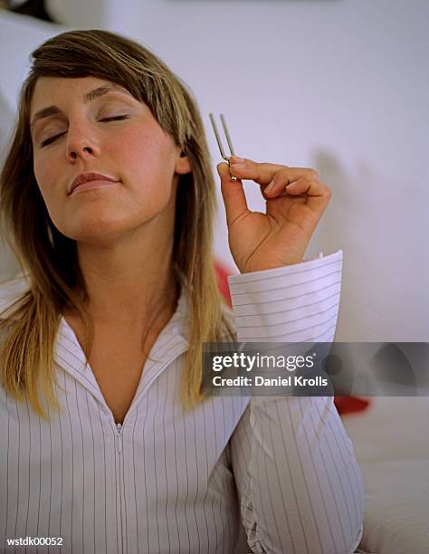 woman holding tuning fork, close up - musikzubehör stock-fotos und bilder