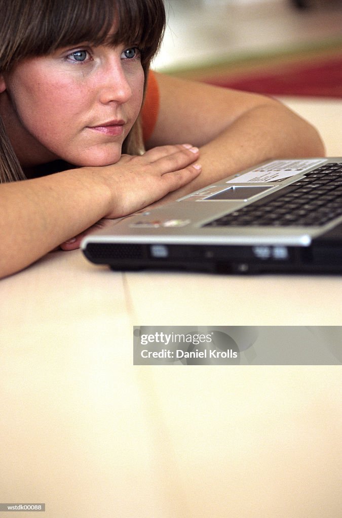 Woman lying, looking at laptop