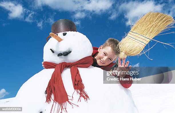 boy standing behind snowman with broomstick - water form stock pictures, royalty-free photos & images