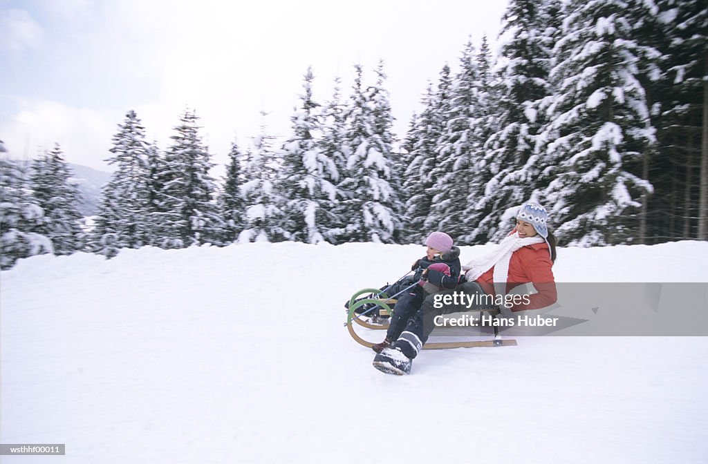 Woman and child riding on sledge
