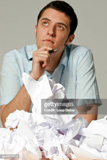 young man sitting at desk with crumpled paper - schreibgerät stock-fotos und bilder