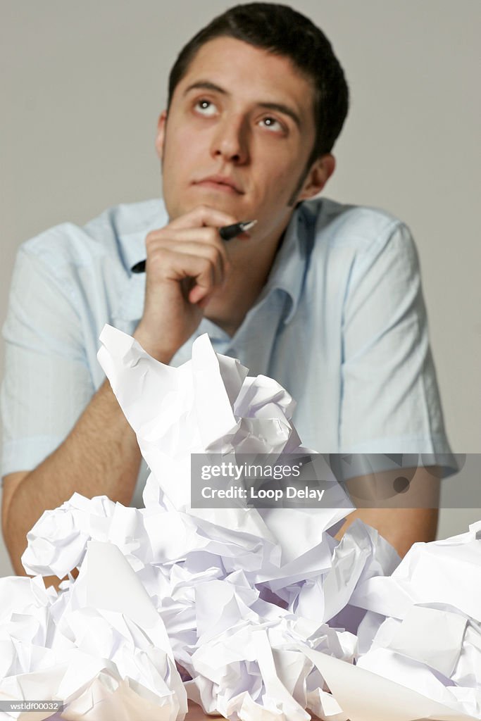 Young man sitting at desk with crumpled paper