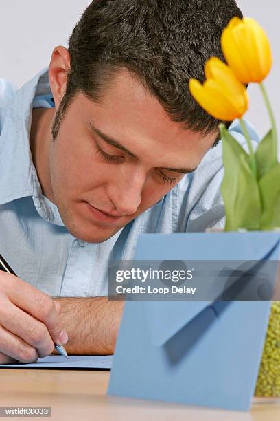 young man writing a letter - writing instrument fotografías e imágenes de stock