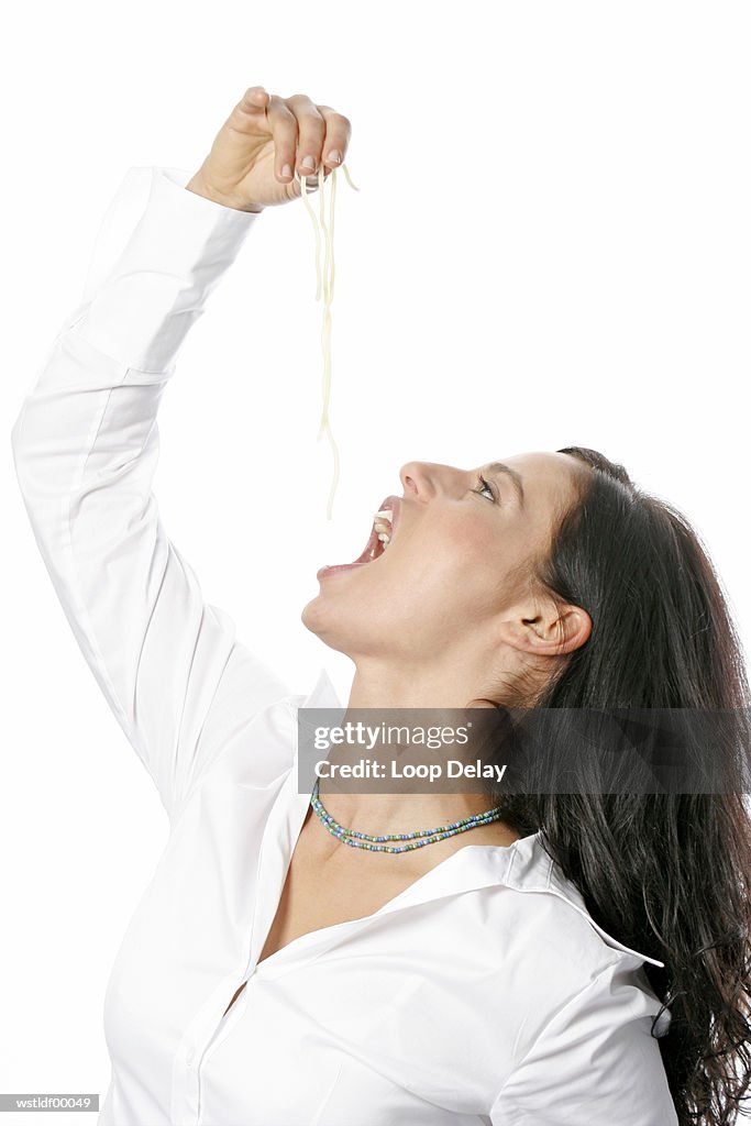 Young woman holding noodles in hand above mouth