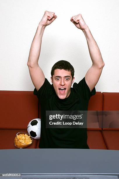 young man watching tv, punching the air - entertainment best pictures of the day april 28 2016 stockfoto's en -beelden