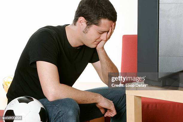 disappointed young football fan holding head in hand - recreational equipment stock pictures, royalty-free photos & images