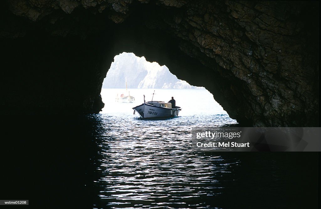 Fishing boat sailing through cave in water, l'Estartit, Costa Brava, Catalonia, Spain