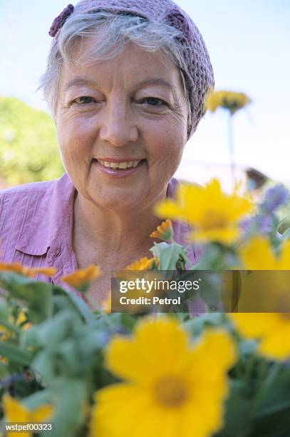 senior woman in front of flowers, close up - up do foto e immagini stock