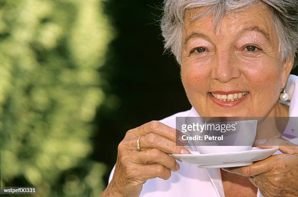 senior woman holding cup of coffee, close up - of fotografías e imágenes de stock