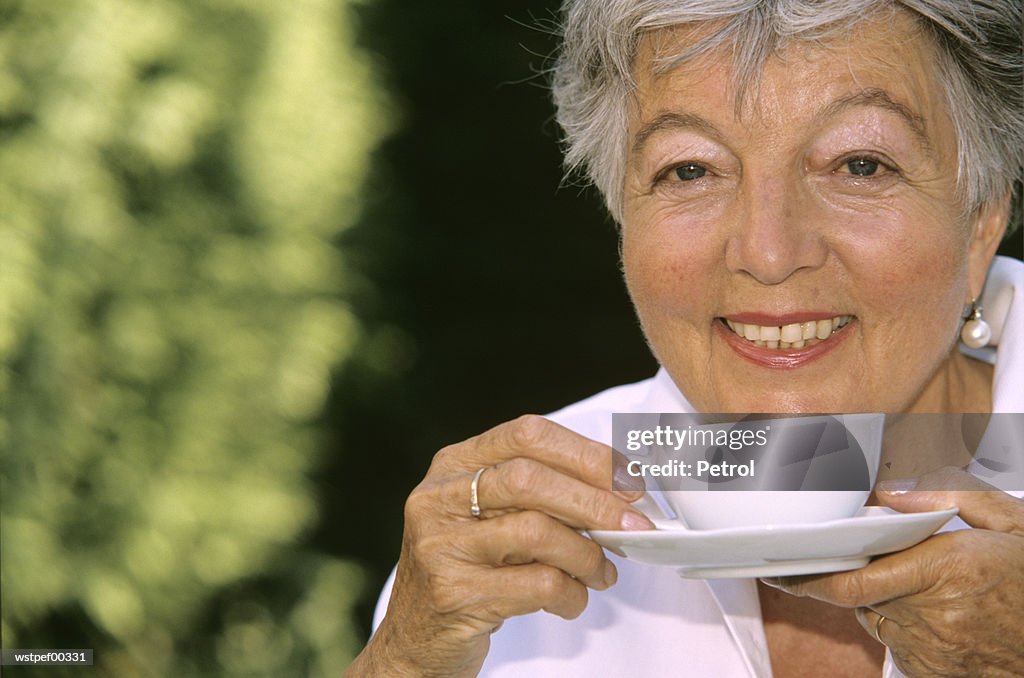 Senior woman holding cup of coffee, close up