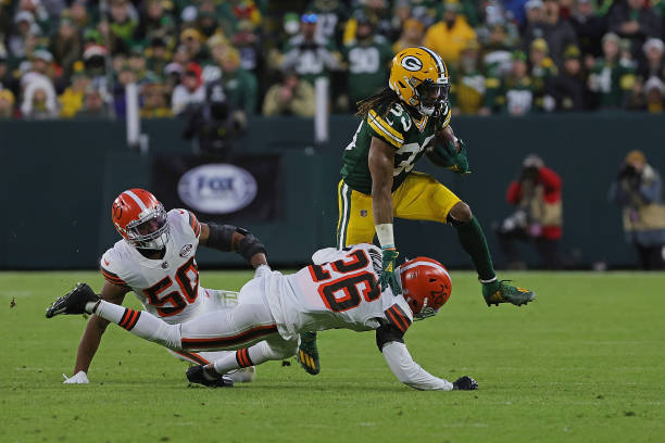 Aaron Jones of the Green Bay Packers s tripped up by Greedy Williams of the Cleveland Browns during a game at Lambeau Field on December 25, 2021 in...