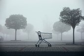 Abandoned shopping cart on parking lot in thick fog
