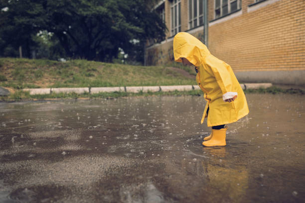 adorable petit garçon jouant au jour de pluie - averse photos et images de collection