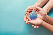 Adult and child hands holding paper cut water drop, World Water Day,  Clean water and sanitation, CSR, save water,  ecology concept