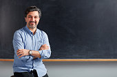 Adult teacher posing on blackboard.