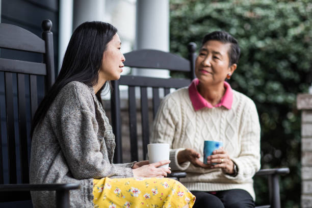 adult woman and senior mother talking on front porch - asian old mother and middle aged daughter stock pictures, royalty-free photos & images