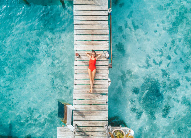 aerial shot of womann relaxing in a water bungalow - vacations stock pictures, royalty-free photos & images