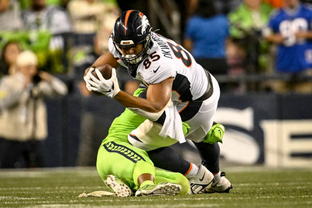 Albert Okwuegbunam of the Denver Broncos stretches for a first down as Quandre Diggs of the Seattle Seahawks makes the stop during the second half of...