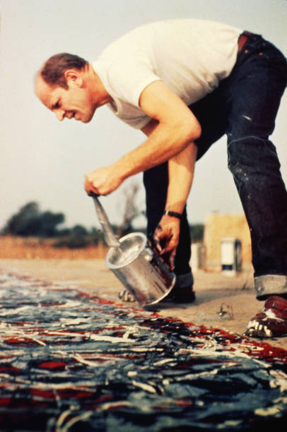 American abstract expressionist artist Jackson Pollock works on a painting at his studio, East Hampton, New York, 1950.