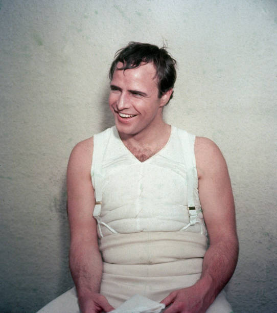 American actor Marlon Brando laughs while wearing body padding for his role as French emperor Napoleon Bonaparte in the film, `Desiree,` directed by...