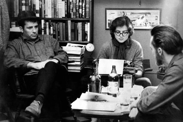 American writers Jack Kerouac and Lew Welch sit around a low table as they collaborate on a poem, which is typed by Gloria Schoffel in the apartment...