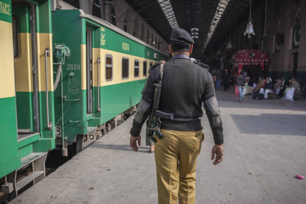 An armed police officer patrols a platform next to a Green Line Express train an express service operated by Pakistan Railways between Islamabad and..