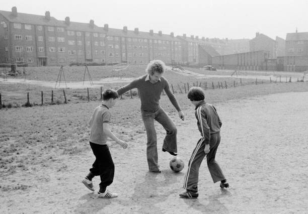 Andy Gray of Aston Villa and Scotland playing football with local children on a housing estate near his mothers home in Drumchapel, Glasgow, circa...