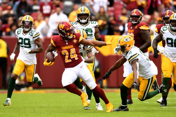 Antonio Gibson of the Washington Commanders looks to avoid a tackle by Adrian Amos of the Green Bay Packers during the third quarter at FedExField on...