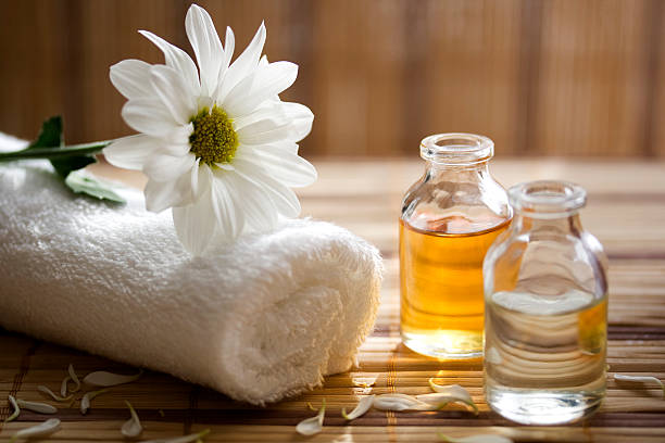 aroma therapy oils placed next to a white towel and flower - oil stock pictures, royalty-free photos & images