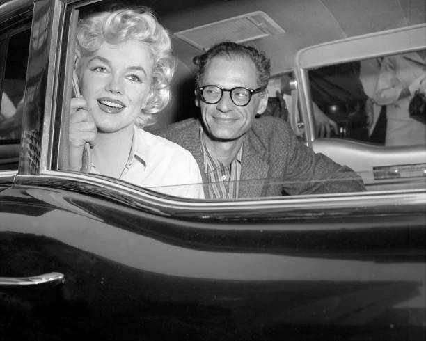 Arthur Miller, the playwright, gazes` adoringly at his wife, Marilyn Monroe, as they drive away from Lenox HIll Hospital. The dazzling film star was...