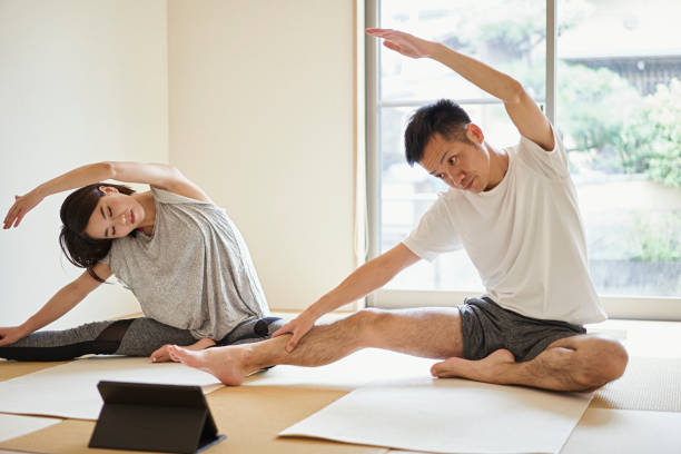asian couple stretching exercises with digital tablet in the japanese-style room at home. - exercise stock pictures, royalty-free photos & images
