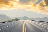asphalt road and mountains with foggy landscape at sunset