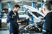 Auto mechanic working with car diagnostic tool in a repair shop.