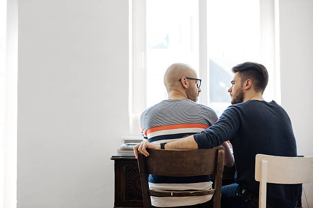 back shot of gay couple sitting together - couple talking stock pictures, royalty-free photos & images