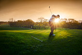 backlit golf course with golfer chipping onto green