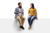 Bearded man talking to a young female seated on a banner