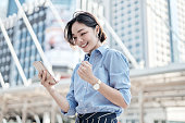 A beautiful Asian business woman is looking at her smartphone and very happy.