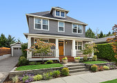 Beautiful craftsman home exterior on bright sunny day with green grass and blue sky