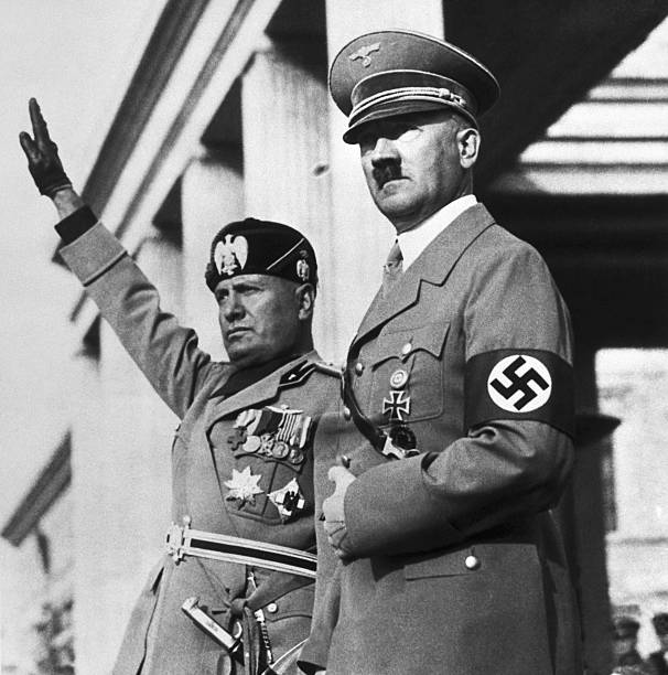 Benito Mussolini and Adolf Hitler watch a Nazi parade staged for the Italian dictators's visit to Germany.