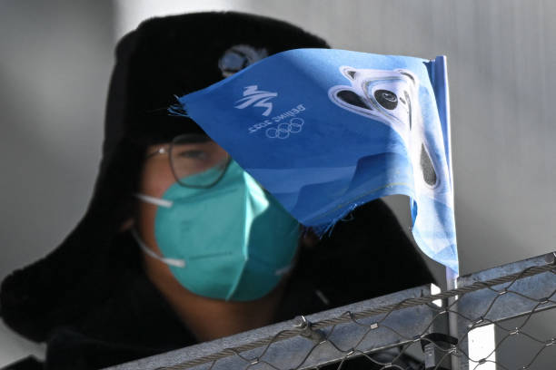 Bing Dwen Dwen, the mascot for the Beijing 2022 Winter Olympic Games, is seen on a flag next to a member of Chinese security personnel ahead of the...