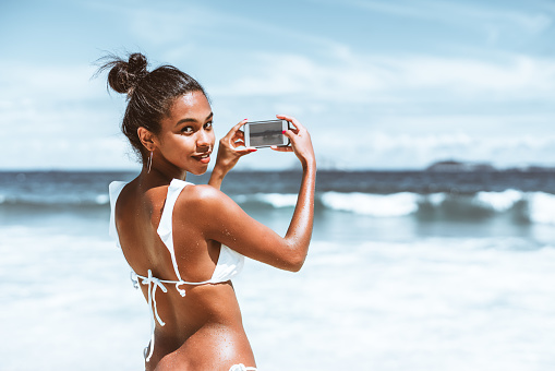 Black girl with smartphone on the beach