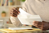 Black man hands putting a letter inside an envelope