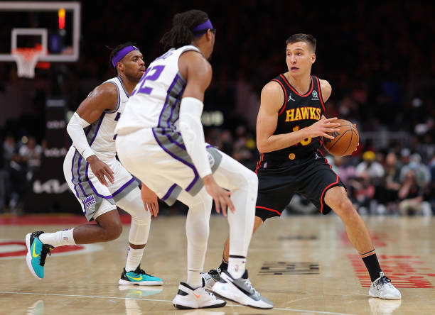 Bogdan Bogdanovic of the Atlanta Hawks is defended by Richaun Holmes and Buddy Hield of the Sacramento Kings during the second half at State Farm...