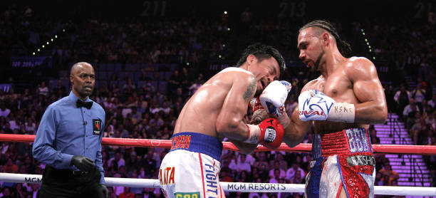 Boxer Keith Thurman slams a right to the face of Filipino boxer Manny Pacquiao as referee Kenny Bayless looks on during their WBA super world...