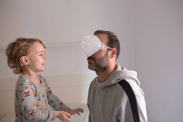 boy laughing at dad after putting surgical mask in eyes - funny surgical masks stock pictures, royalty-free photos & images