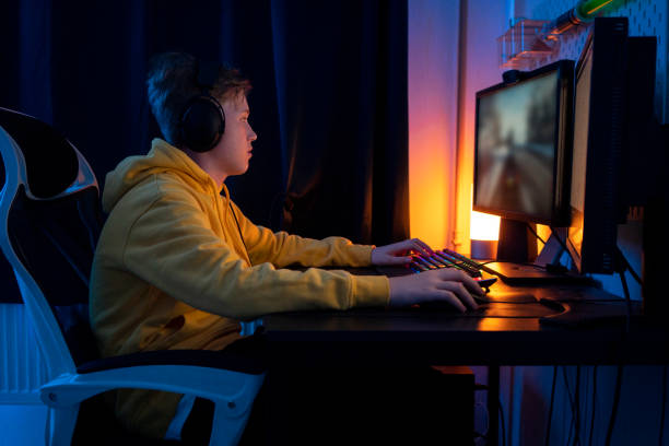 boy playing game on desktop pc on table at home - streaming - fotografias e filmes do acervo