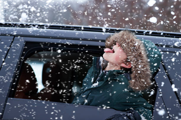boy tasting snow through car window during snowfall - snow stock pictures, royalty-free photos & images